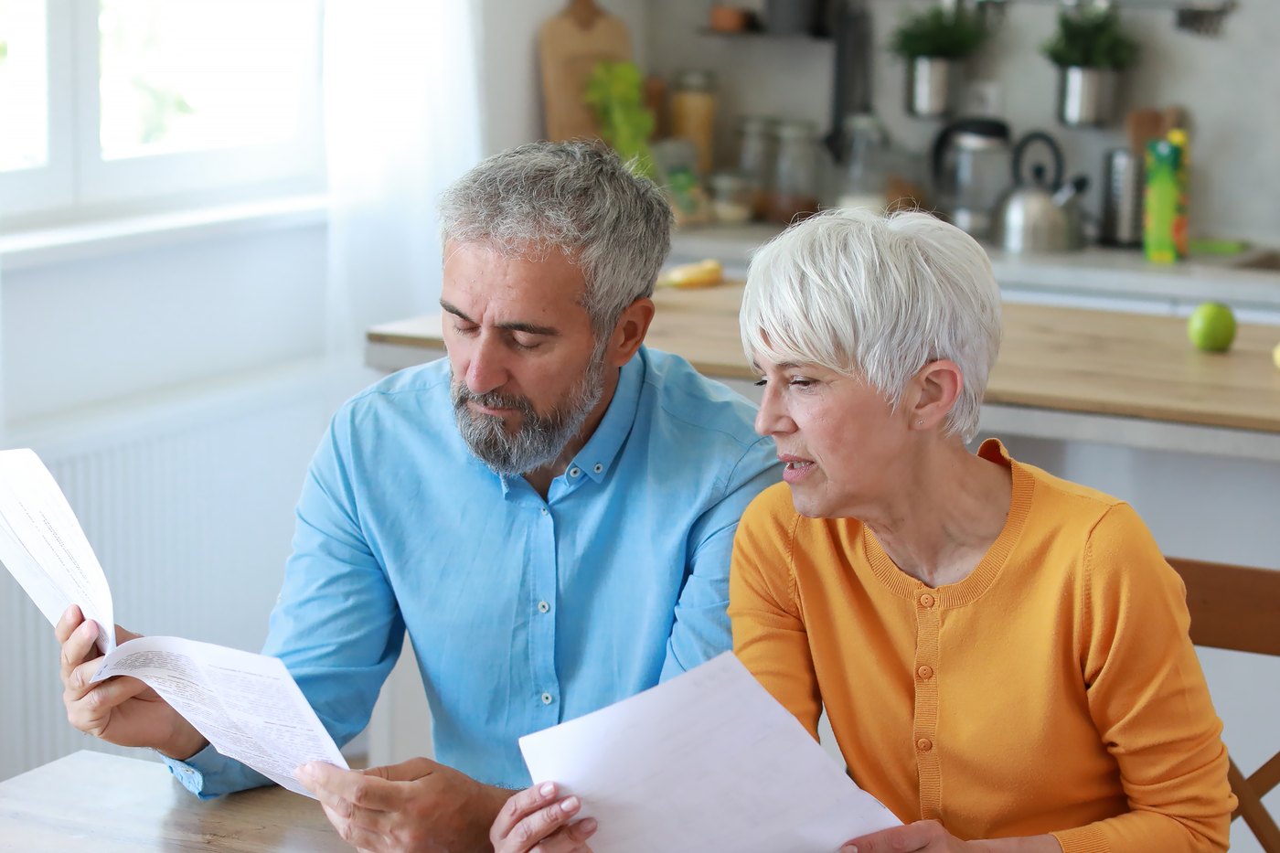 A couple reviewing documents together at their kitchen table.